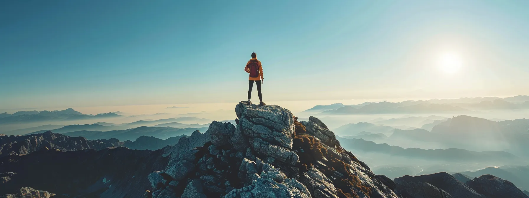 a person standing on top of a mountain peak, looking out at the expansive view below.