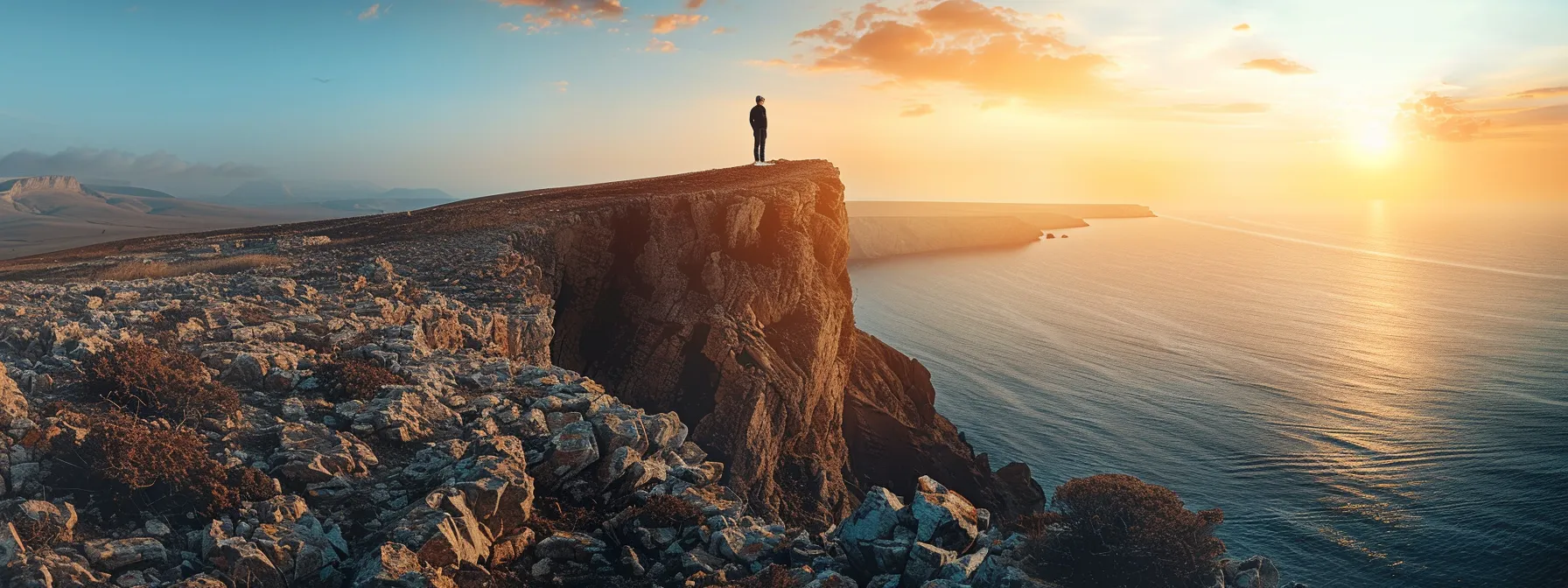 a person standing at the edge of a cliff, looking out at the vast horizon with determination.