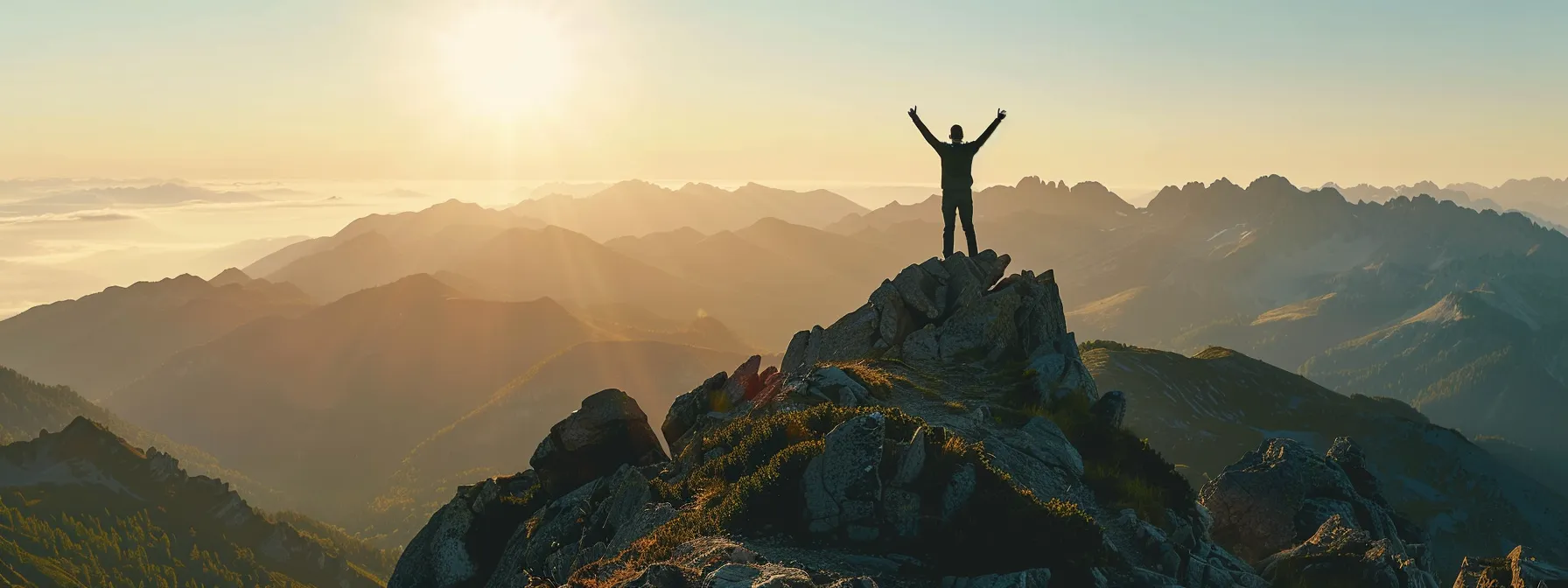 a person standing on a mountaintop with arms raised in triumph.